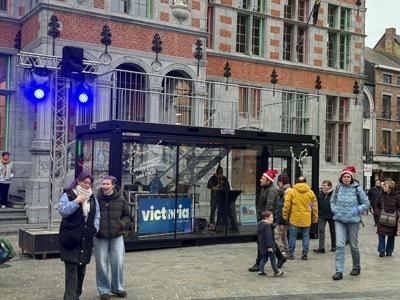 Conteneur vitré avec lettrage adhésif au marché de Noël de Hal, avec vue sur l'hôtel de ville historique